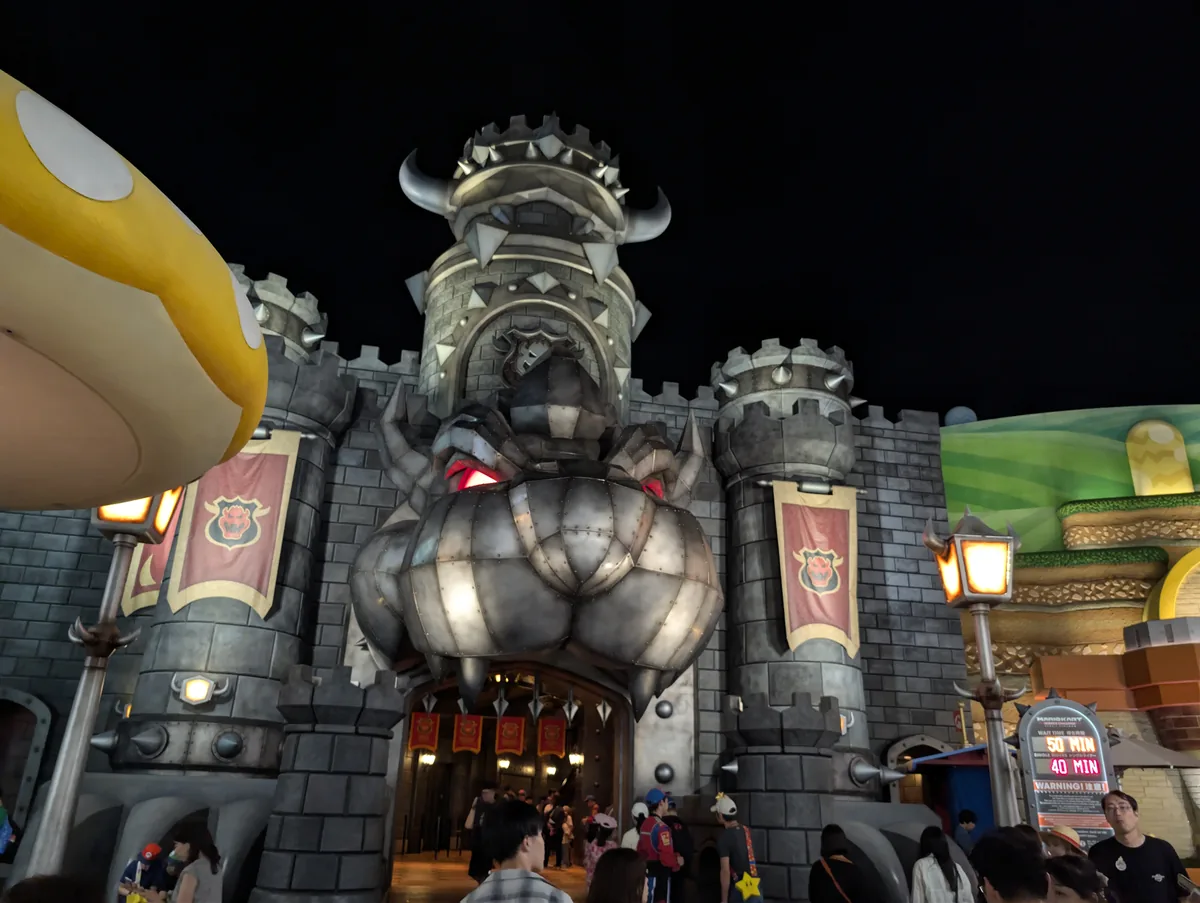 夜のクッパ城。迫力のある表情と石造りの装飾がライトアップされ、マリオカートへ向かう気分が高まります。